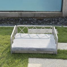 a white dog bed sitting on top of green grass in front of a blue door