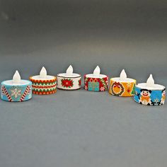 several colorful candles are lined up on a gray surface