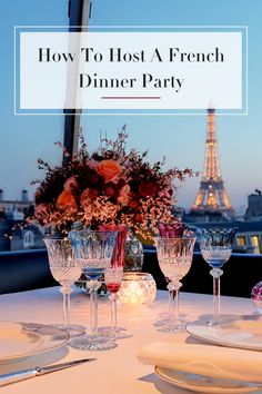 a table with wine glasses and plates on it in front of the eiffel tower