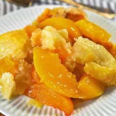 a white plate topped with orange slices and crumbled toppings next to a fork