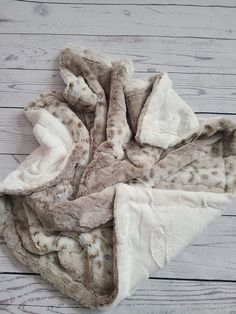 a pile of white and brown fur on top of a wooden floor next to a piece of wood