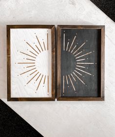 two framed artwork pieces on top of a white table