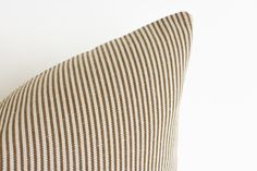 a brown and white striped pillow sitting on top of a bed