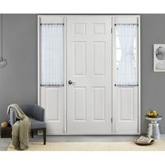 a living room with two white doors and a gray chair in front of the door