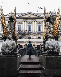 a person walking across a bridge with statues