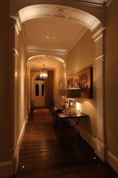 a hallway with a table and lamps in it