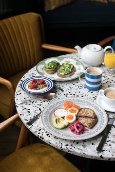 a table topped with plates of food next to cups of coffee and orange juices