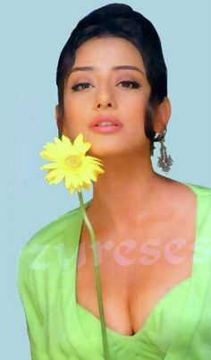 a woman holding a yellow flower in her right hand and looking up at the camera