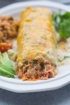 a white plate topped with meat and veggie enchilada next to lettuce