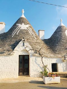 an old white building with three thatched roofs