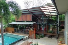 a house with a pool in the middle and people sitting on the deck near it