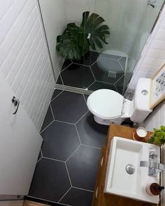 a small bathroom with a toilet, sink and shower stall in it's corner