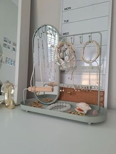 a desk with a mirror, jewelry holder and other items on the counter top in front of it