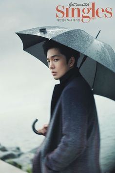 a man holding an umbrella while standing next to the ocean