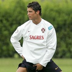 a man standing on top of a soccer field wearing a white shirt and black shorts