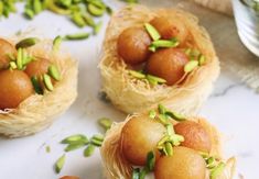 three small baskets filled with food sitting on top of a white tablecloth next to green leaves