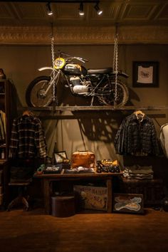 an old motorcycle is on display in a room with other items, including clothing and memorabilia