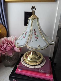 a lamp sitting on top of a table next to a vase filled with pink flowers