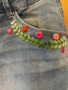 a pair of jeans with embroidered flowers on them