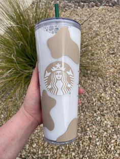 a hand holding a starbucks cup in front of some grass