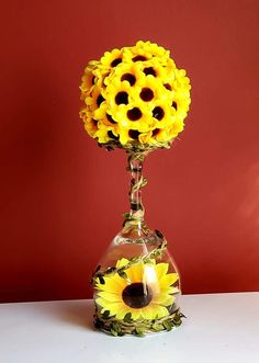 a vase filled with yellow sunflowers on top of a white table next to a red wall