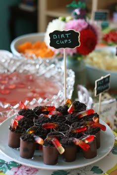 desserts with dirt cups and candy sticks on a table in front of other desserts