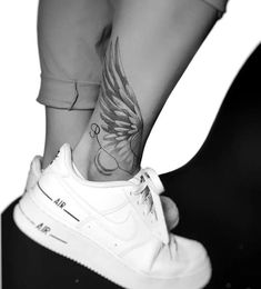 black and white photograph of a woman's foot with wings tattooed on her ankle