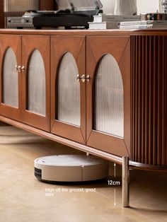 a roomba that is sitting on the floor next to a cabinet