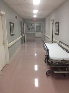 an empty hospital hallway with two beds on wheels