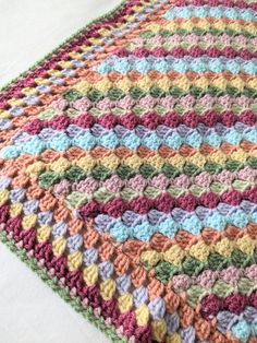 a multicolored crocheted blanket laying on top of a bed