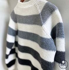 a striped sweater hanging on a clothes hanger in front of a white and gray wall