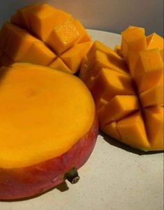 there are two pieces of mango on the plate and one is cut into cubes