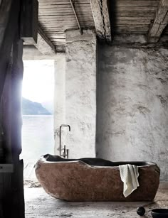 a large stone bathtub sitting in the middle of a room next to a window