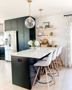 a kitchen with white counter tops and wooden stools in front of an island that has flowers on it