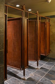 three wooden partitions in a room with tile flooring and wall mounted lights on the ceiling