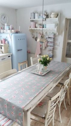 a table with flowers on it in a kitchen next to a refrigerator and stove top oven