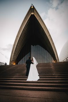 a bride and groom standing on the steps of sydney opera house