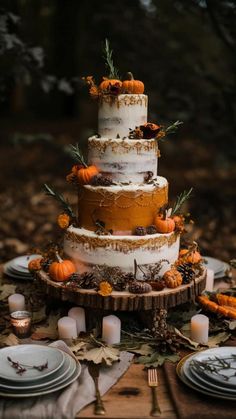 a three tiered cake sitting on top of a wooden table surrounded by plates and candles