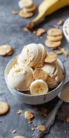 a bowl filled with ice cream and banana slices next to crackers on a table