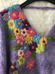 a purple sweater with colorful flowers on it