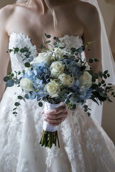 a bride holding a bouquet of white and blue flowers