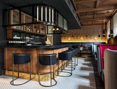 a bar with several stools in front of it and lights on the back wall