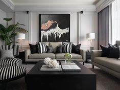 a living room with black and white striped couches, coffee table and art on the wall