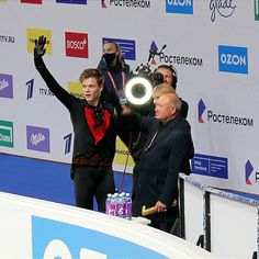 two men standing on top of a podium with their hands in the air and one man holding his arms up