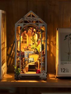 a doll house is lit up on a shelf next to two boxes with plants in them