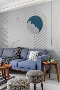 a living room with a blue couch and two stools in front of the wall