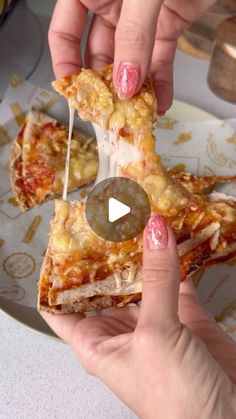 two hands holding slices of pizza on a plate