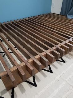 a wooden bed frame sitting on top of a white carpeted floor next to a blue wall