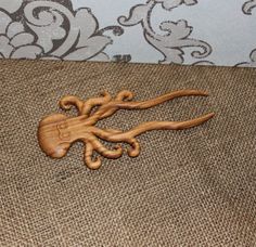 an octopus carved from wood sitting on top of burlocked fabric next to wallpaper