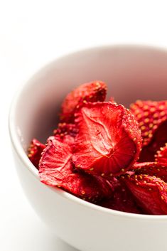 a white bowl filled with red flowers on top of a table